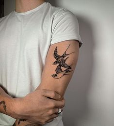 a man with a bird tattoo on his arm and shoulder is holding the other arm