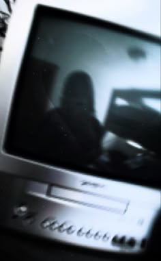 a blurry image of a person sitting in front of a television set with the screen turned on