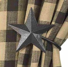 a black and white star hanging on the side of a curtain with plaid curtains behind it