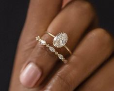 a woman's hand holding a diamond ring with two diamonds on the middle finger