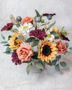 a vase filled with flowers on top of a white cloth covered table next to a wall