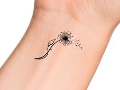 a small black dandelion tattoo on the left side of the wrist is shown