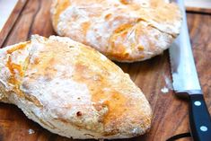 two loaves of bread on a cutting board with a knife