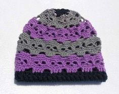 a crocheted hat is shown on a white surface with grey and purple trim