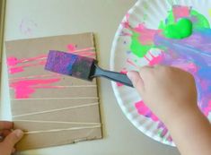 a person using a paintbrush to decorate a paper plate