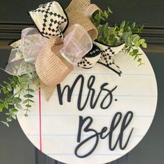 a door hanger that says mrs bell on it with a bow and some greenery