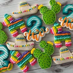 decorated cookies are arranged on a table with the word fiesta written in large letters and cactus decorations