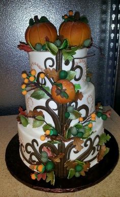 a three tiered cake decorated with pumpkins and leaves