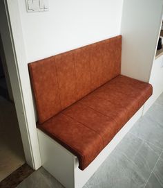 a brown leather couch sitting on top of a white counter next to a wall mounted electrical outlet