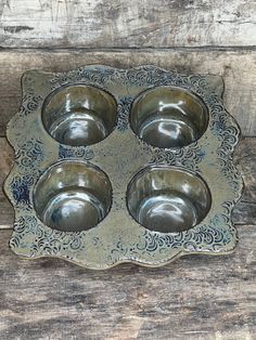 four metal bowls sitting on top of a wooden table