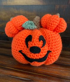 an orange crocheted pumpkin with a bow on it's head is sitting on a wooden surface