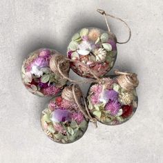 four ornaments with flowers are hanging from twine