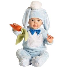 a baby wearing a bunny suit and holding a flower in his hand while sitting on the ground