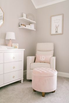 a baby's room with a white chair and pink ottoman in the middle of it