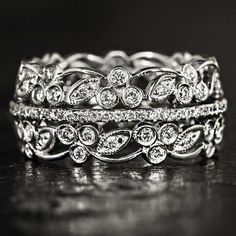 two wedding bands with diamonds on them sitting on a black surface in front of a dark background