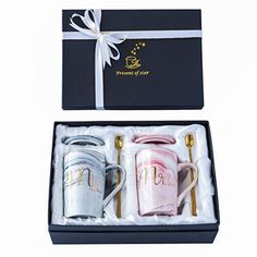 two coffee mugs in a gift box with a ribbon around the top and bottom