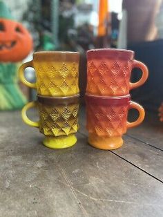 three different colored mugs sitting on top of a table