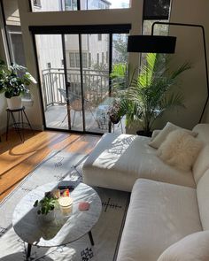 a living room filled with white furniture and lots of plants on top of the table