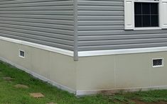 a dog standing in front of a gray house with white trim on it's windows