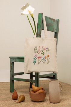 a white flower sitting on top of a wooden chair next to a potted plant