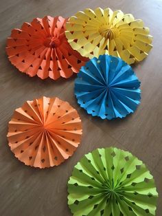 four different colored paper fans laying on the floor