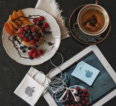 two plates with desserts on them next to a cup of tea and an ipad