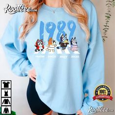 a woman wearing a blue sweatshirt with cartoon characters on it