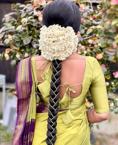 the back of a woman's head with braids and flowers in her hair