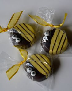 three chocolate covered candies with googly eyes and yellow ribbon tied around the edges