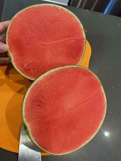 two pieces of watermelon sitting on top of a cutting board