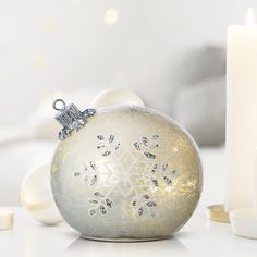 a white christmas ornament sitting on top of a table next to some candles