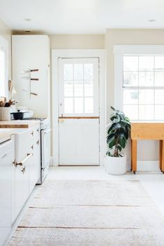 a kitchen with white cabinets and a potted plant on the counter next to an open door