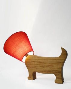 a small wooden dog lamp with a red shade on it's head and tail