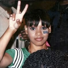 a young woman making the peace sign with her hand and wearing a black band around her eye