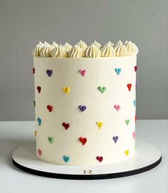 a white cake with multicolored hearts on it