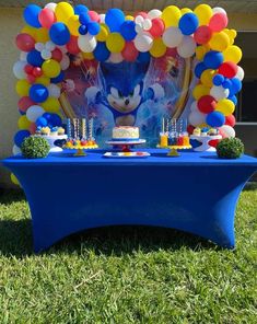 a blue table topped with cake and balloons