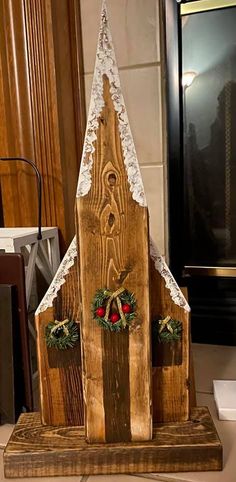 a wooden church with wreaths and bells on it's steeple is sitting on a table