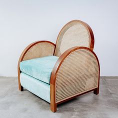 a chair made out of wicker and blue cushion on concrete flooring with white wall in background