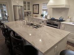 a large kitchen with an island counter top and bar stools in front of it