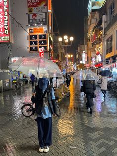 people walking down the street with umbrellas on a rainy night in tokyo, japan