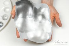 a person holding a silver object in their hand next to some ice cube trays