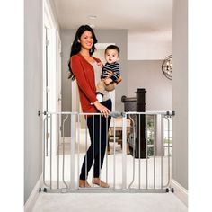 a woman holding a baby in her arms behind a gate with the words fits openings up to 5'wide