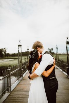 a bride and groom kissing on a bridge