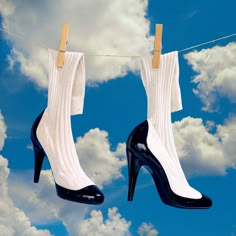 pair of high heeled shoes hanging on clothesline with sky and clouds in background