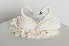 two white swans sitting next to each other on a table