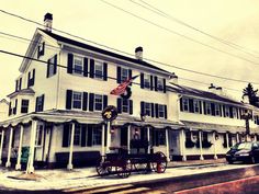 a horse and buggy parked in front of a white building with an american flag on it