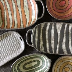 four ceramic bowls sitting on top of a black table next to each other with different designs