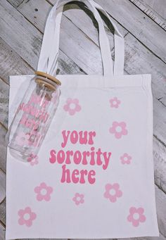 a white tote bag with pink flowers and the words your sorority here on it