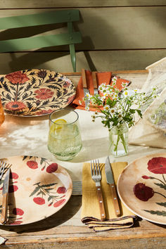 the table is set with plates, silverware and flowers