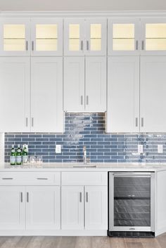 an empty kitchen with white cabinets and blue glass tile backsplashes on the wall